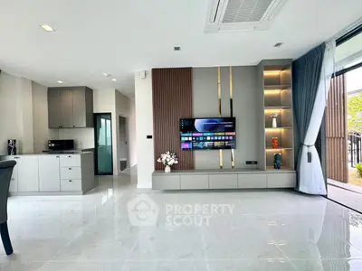 Modern living room with sleek TV unit and open layout, featuring elegant decor and natural light.