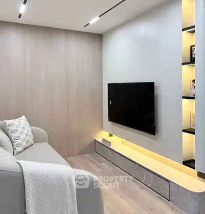 Modern living room with sleek TV setup and cozy sofa in stylish apartment.