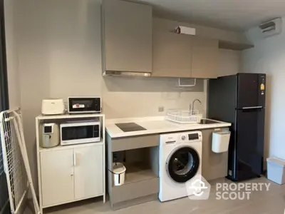 Modern kitchen with appliances including washing machine and fridge in compact layout.