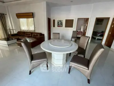 Spacious living room with elegant round dining table and leather sofa, perfect for modern family gatherings.