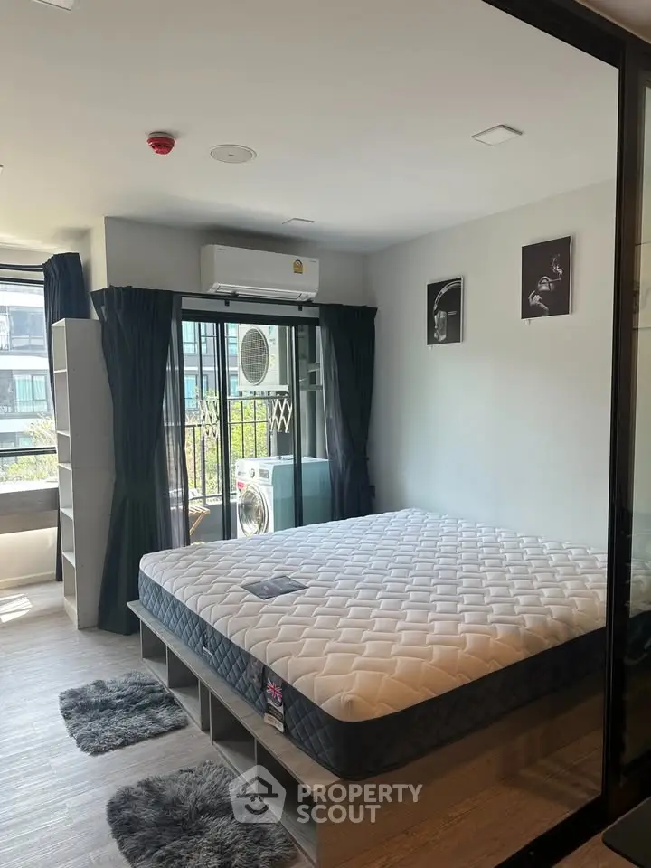 Modern bedroom with large window, stylish decor, and ample natural light in a contemporary apartment.