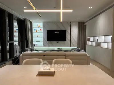 Luxurious modern living room with sleek design and ambient lighting, featuring a large TV and elegant shelving.