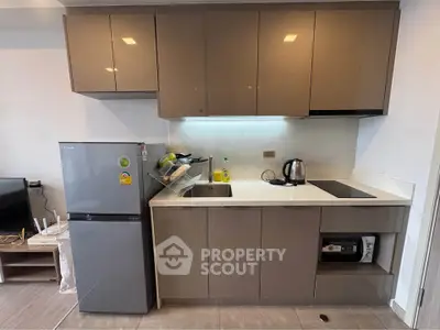 Modern kitchen with sleek cabinets, fridge, and electric stove in a compact layout.
