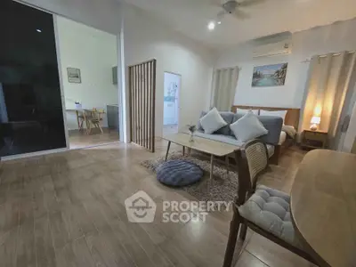 Spacious modern living room with wooden flooring and cozy decor in a stylish apartment.