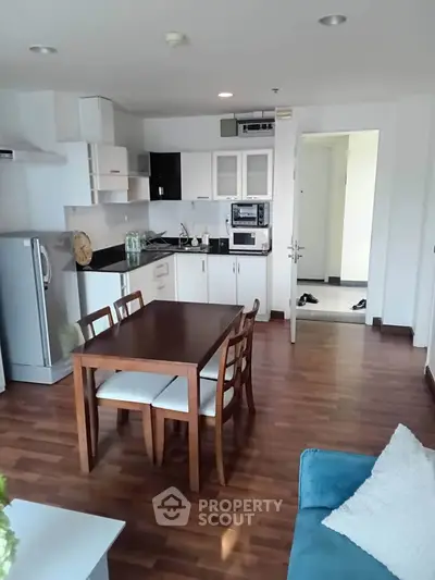 Modern open-layout kitchen and dining area with wooden flooring and sleek appliances.