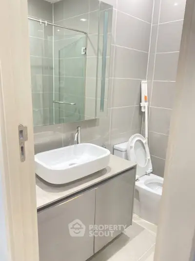 Modern bathroom with sleek fixtures and neutral tiles, featuring a stylish vanity and mirror.