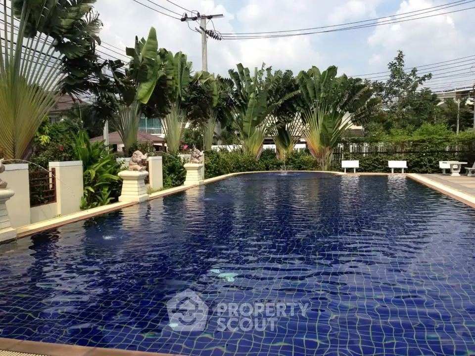 Luxurious outdoor pool surrounded by lush greenery in a serene residential area.