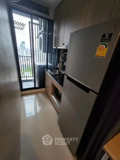 Compact kitchen with modern appliances and city view from balcony.