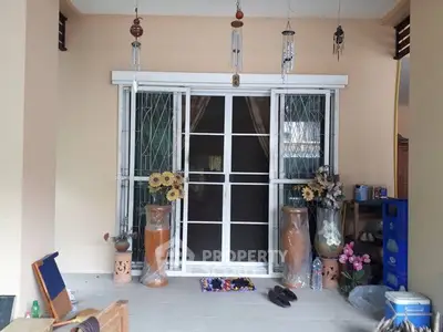 Charming home entrance with decorative vases and wind chimes, inviting ambiance for potential buyers.