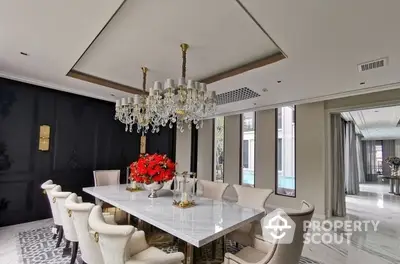 Luxurious dining area with elegant chandelier, marble table, and plush chairs, complemented by sophisticated dark walls and sleek flooring.