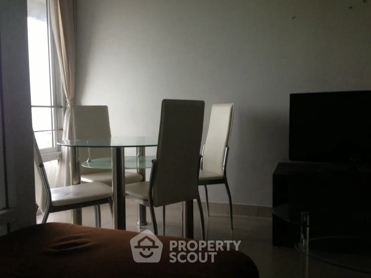 Modern living room with glass dining table and sleek chairs, perfect for urban living.