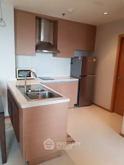 Modern kitchen with sleek wooden cabinets and stainless steel appliances in a stylish apartment.