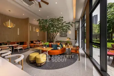 Modern cafe interior with stylish seating and large windows overlooking greenery.