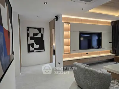 Modern living room with sleek design and large TV, featuring stylish lighting and contemporary art.