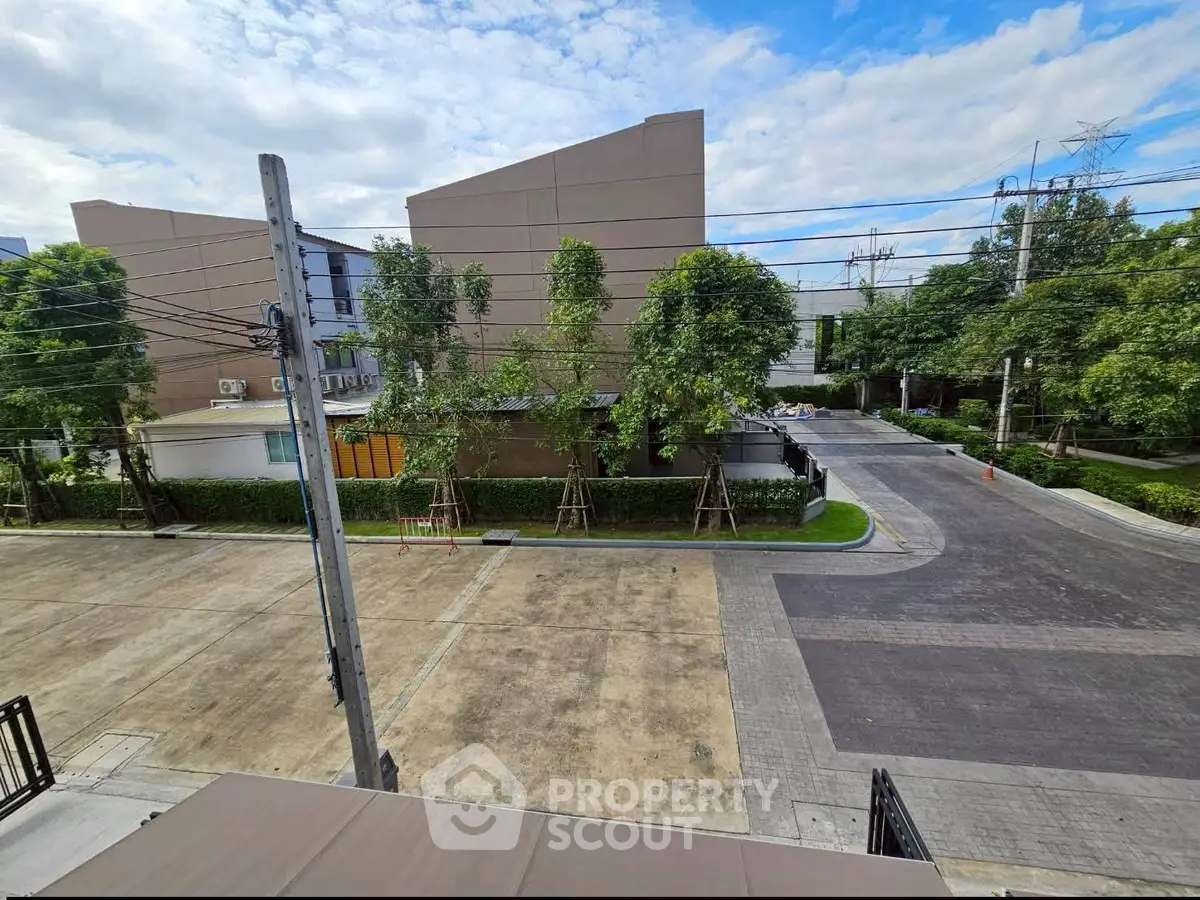 Modern residential area with lush greenery and clear blue sky, showcasing a serene neighborhood view.