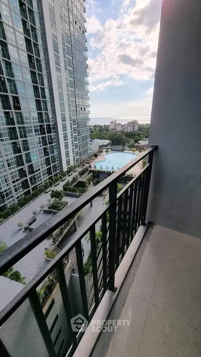 Stunning high-rise balcony view overlooking pool and cityscape, perfect for urban living.
