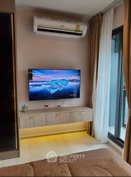 Modern living room with wall-mounted TV and air conditioning, featuring elegant decor and natural light.