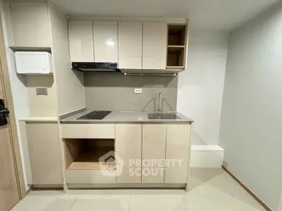 Modern minimalist kitchen with sleek cabinetry and integrated sink in a compact layout.