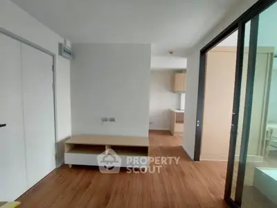 Modern minimalist apartment interior with wooden flooring and sliding glass doors.