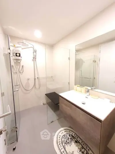 Modern bathroom with glass shower and sleek vanity in bright setting