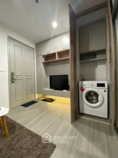 Modern apartment interior with washing machine and TV in compact living space.