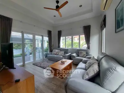 Spacious living room with modern furniture and large windows overlooking a garden.
