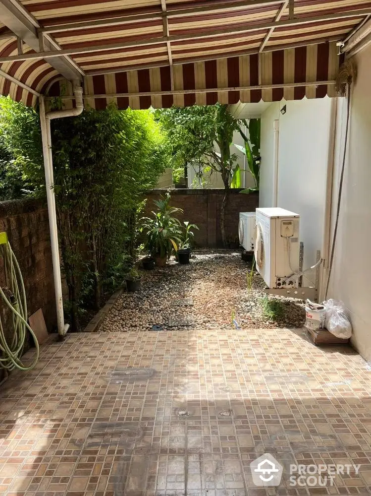 Charming private patio space with terracotta tiles and lush greenery, perfect for outdoor relaxation and entertainment in a serene setting.