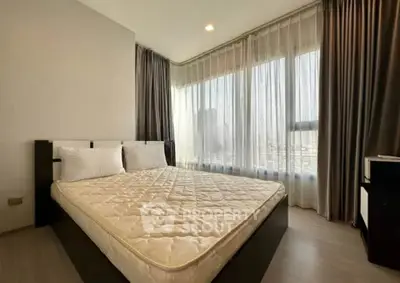Spacious bedroom with large windows and elegant curtains in modern apartment.