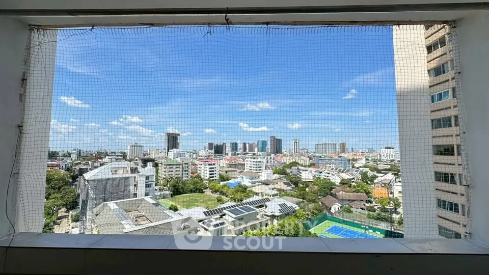 Stunning cityscape view from high-rise building balcony with clear blue sky.
