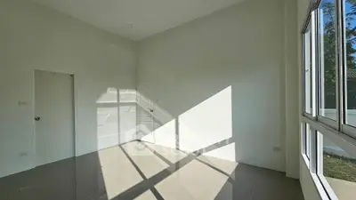 Spacious sunlit room with large windows and sleek tiled flooring, perfect for modern living.