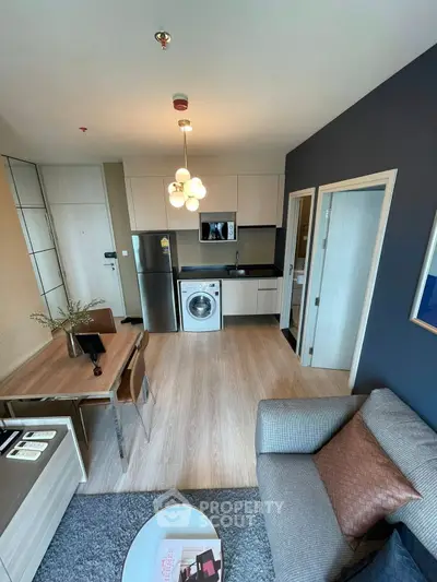 Modern open-plan living room with kitchen featuring sleek appliances and stylish decor.