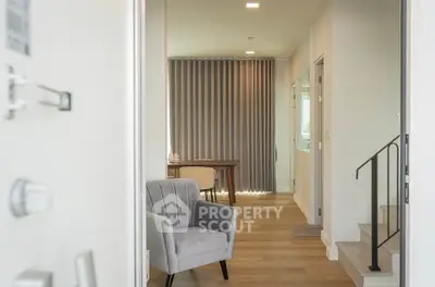 Modern interior with stylish armchair and wooden flooring, leading to a cozy dining area with natural light.