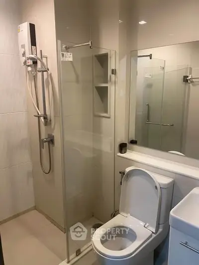 Modern bathroom with glass shower enclosure and sleek fixtures in a contemporary apartment.