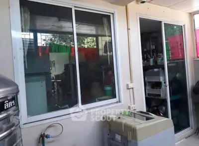 Compact kitchen area with sliding glass door and window, showcasing appliances and storage.