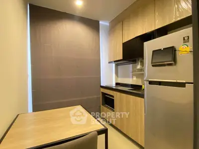 Modern kitchen with sleek cabinetry and stainless steel fridge in a compact layout.
