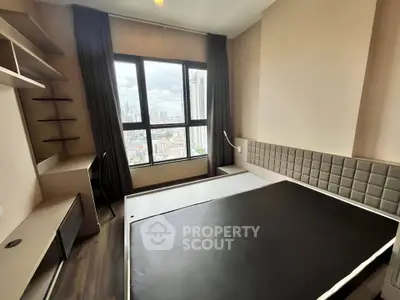 Modern bedroom with city view, featuring sleek furniture and large windows for natural light.