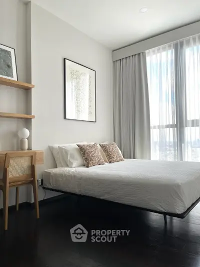 Modern bedroom with elegant decor and large window offering natural light.