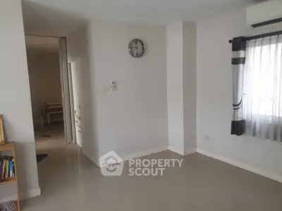 Spacious empty room with clock and window, ideal for customization