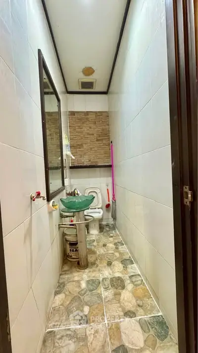 Compact bathroom with stone tile flooring and wall-mounted mirror