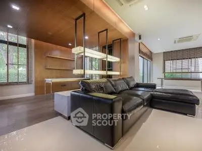 Luxurious modern living room with sleek black leather sofa and elegant wooden accents.