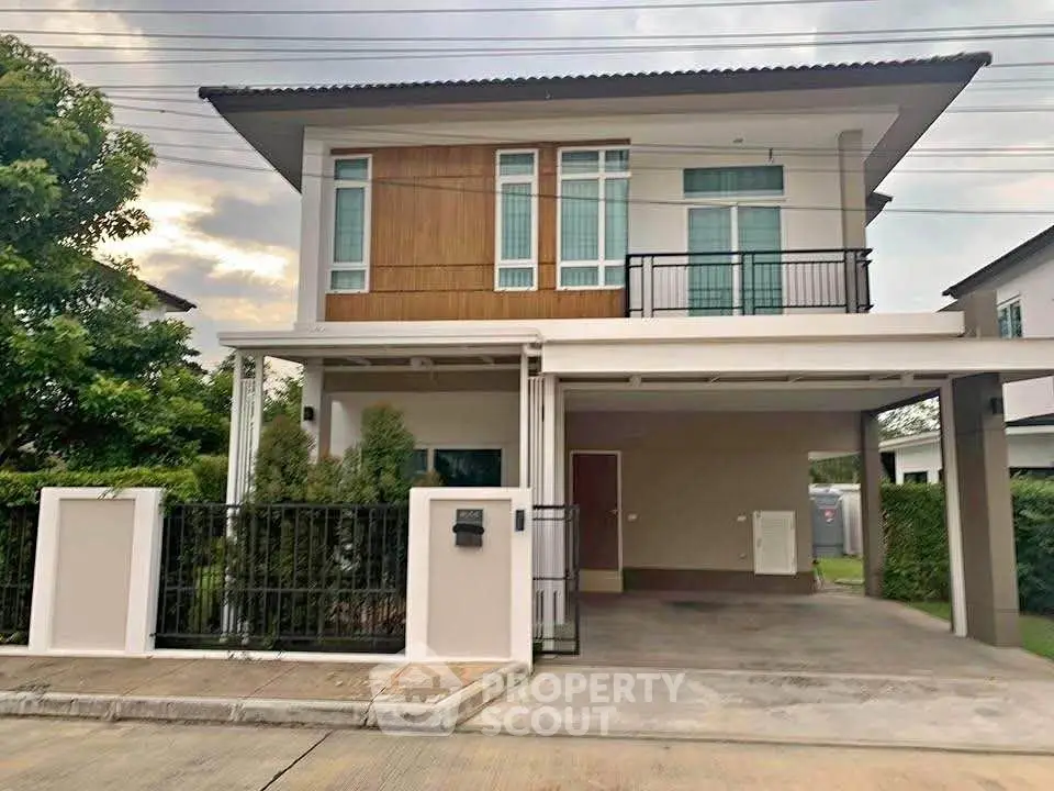 Modern two-story house with carport and lush greenery in a serene neighborhood.