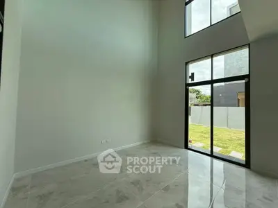 Spacious modern living room with high ceilings and large windows overlooking a garden.