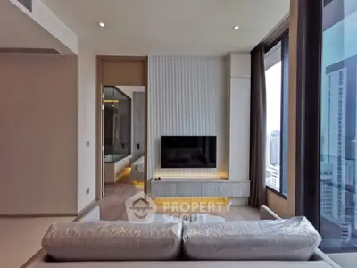 Modern living room with large windows and city view, featuring a sleek TV setup and contemporary design.
