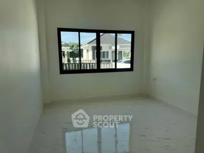Bright empty room with large window and marble floor, overlooking a suburban house.