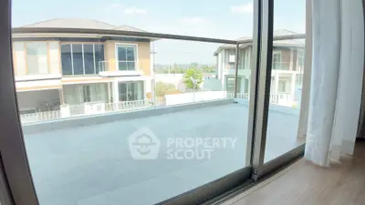 Spacious balcony with sliding glass doors offering a view of modern houses and clear skies.
