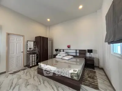 Spacious bedroom with modern furniture and elegant decor, featuring a large bed and ample natural light.