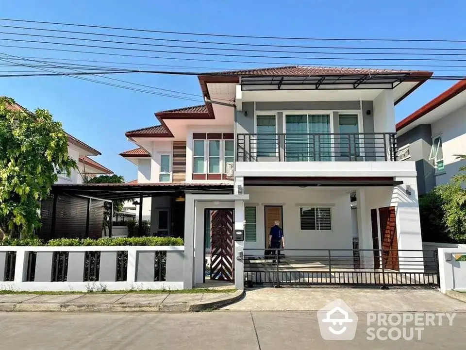 Modern two-story house with balcony and driveway in a suburban neighborhood