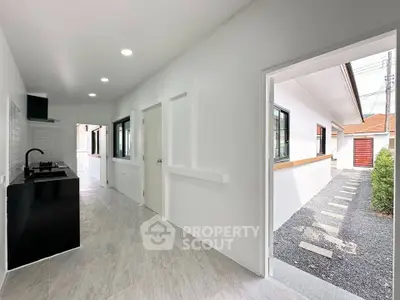 Modern minimalist kitchen with sleek black countertops and open layout leading to outdoor path.