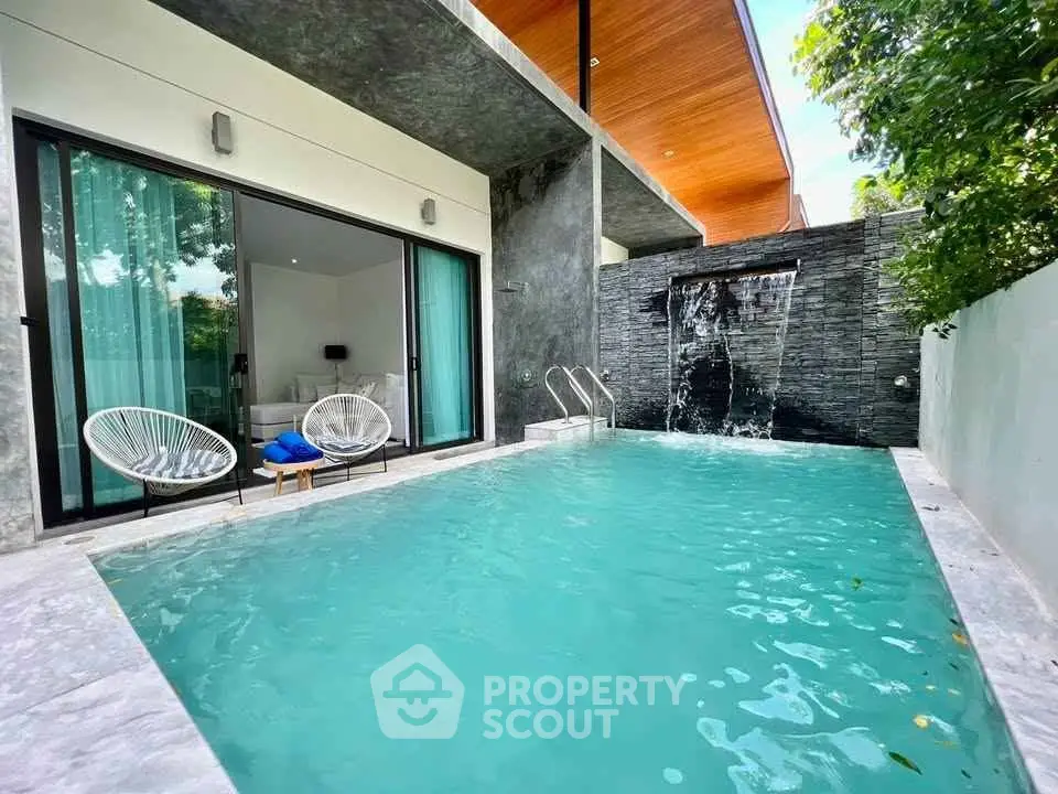 Luxurious private pool with modern design and waterfall feature in a contemporary villa setting.