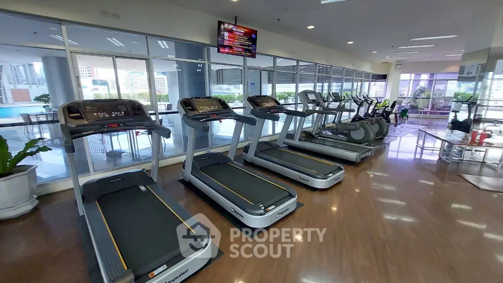 Spacious gym with modern equipment and city view, perfect for fitness enthusiasts.
